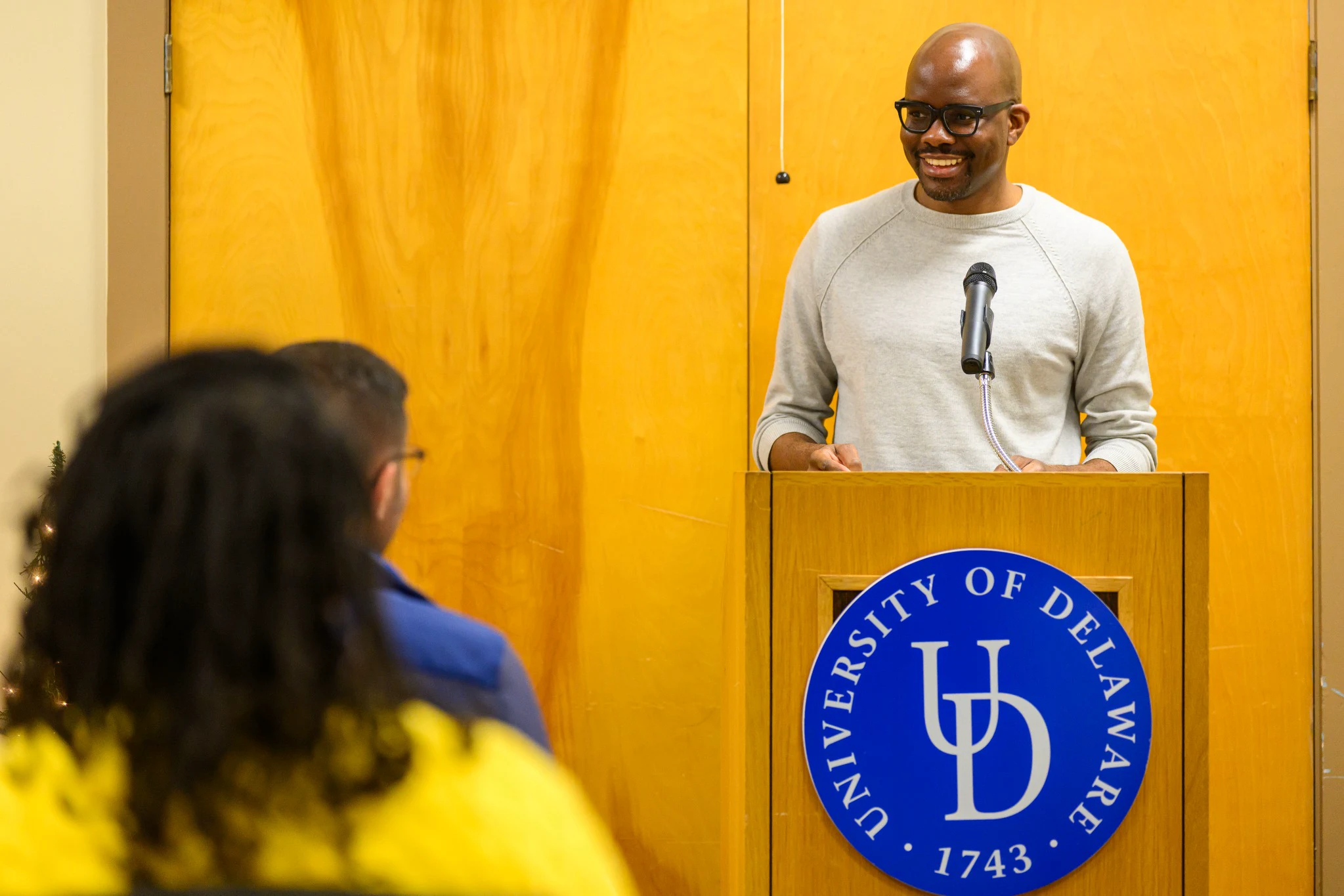 Tope Folarin smiling at the lectern while speaking to an audience at the University of Delaware.